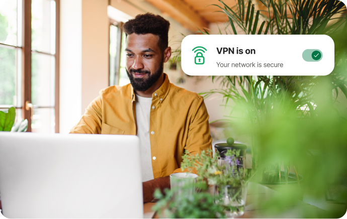 Muž obklopený rostlinami se usmívá na notebook